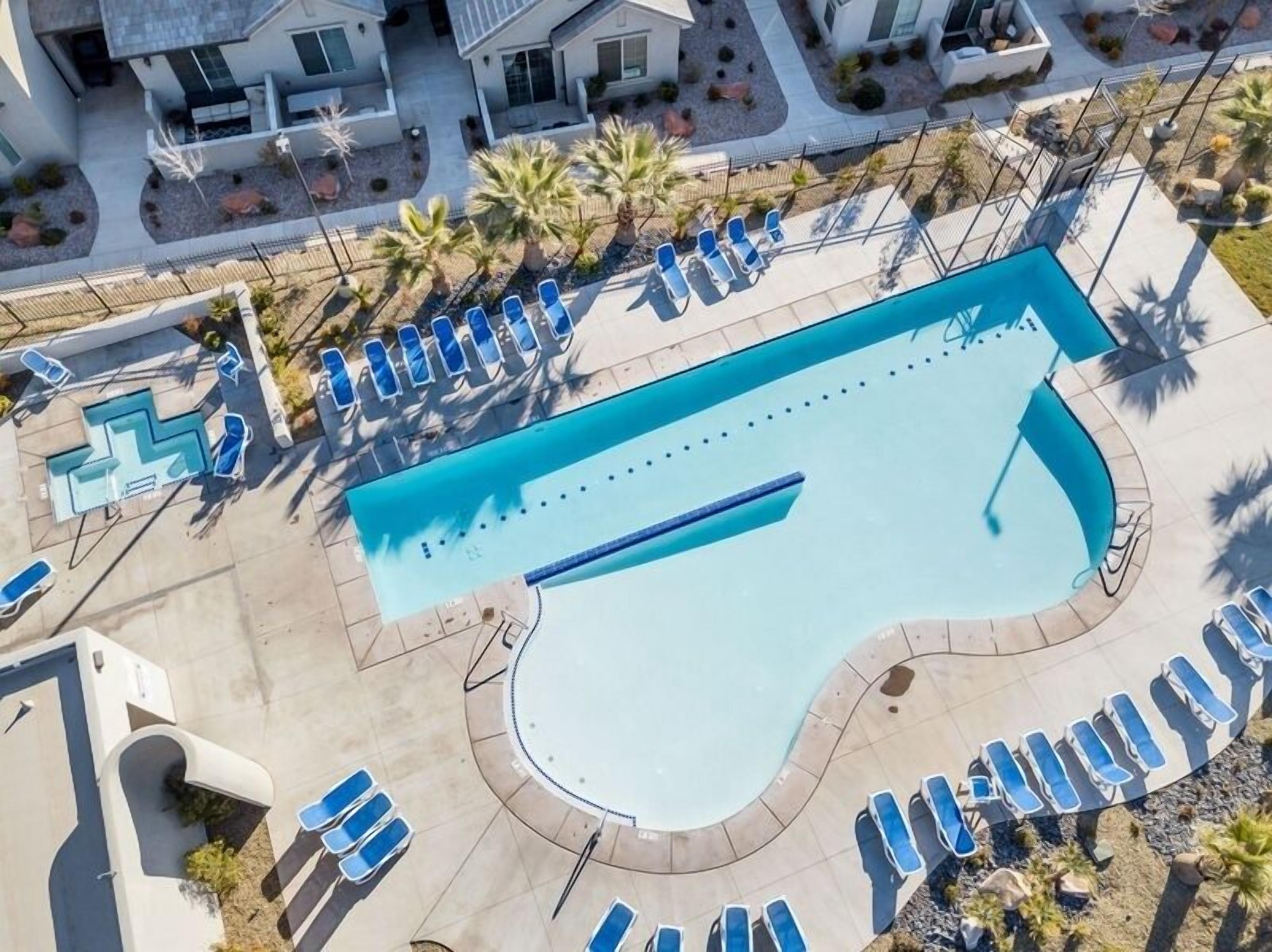 An aerial view of a swimming pool with lounge chairs and palm trees.