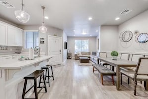 A modern kitchen with white cabinets, a central island with stools, and pendant lighting.