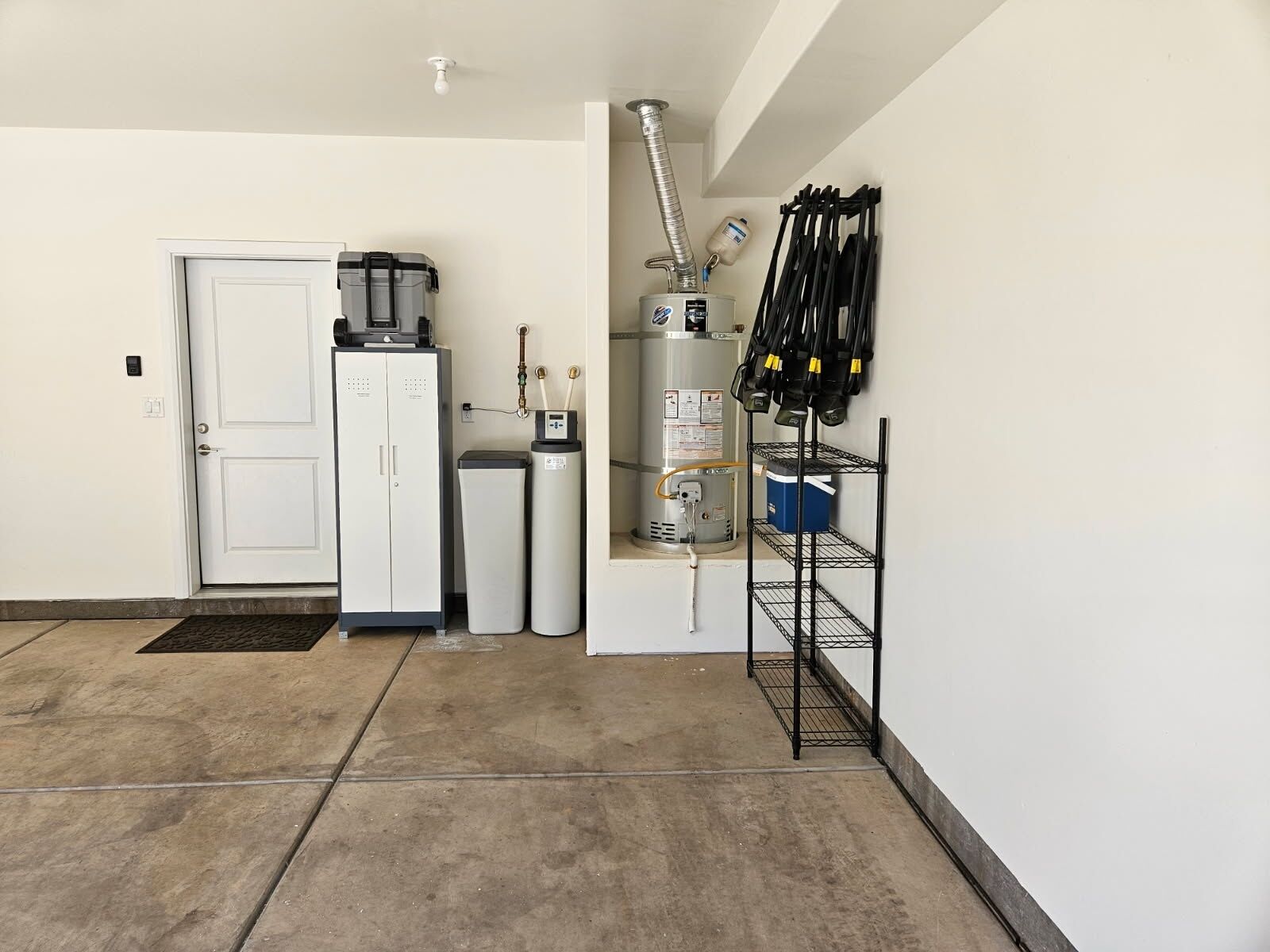 A compact kitchen with a refrigerator, a water heater, and a coffee maker.