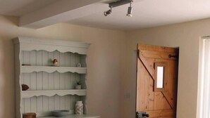 A room with a wooden dining table, white cabinets, and a wooden door. - Blyton 2-bed Cottage, Parking, 30m to Lincoln (Gainsborough)