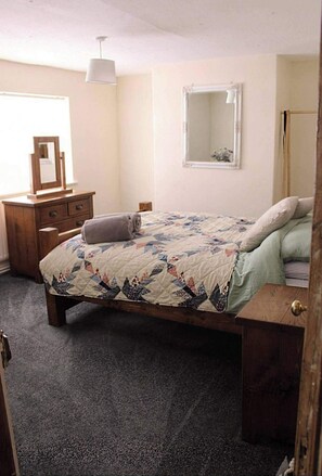 Un dormitorio con cama, cómoda, espejo y ventana.