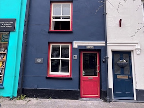 A two-story building with a red door labeled 'GWAIA HOUSE' and a blue door with a basket of flowers. - The Little Laura Ashley House (Machynlleth)