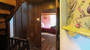 Eine Holztreppe führt zu einem Schlafzimmer mit einem Bett und blumigem Wandpapier.