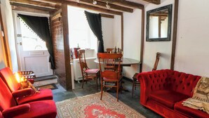 Ein gemütliches Wohnzimmer mit einem roten Sofa, passenden Sesseln, einem Holzesstisch mit Stühlen und einem gemusterten Teppich.