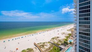 A beach view with a hotel building, a clear sky, and a calm sea.