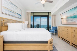 A hotel room with a large bed, a ceiling fan, a TV, a view of the ocean, and a balcony with outdoor seating. - Phoenix Gulf Shores Ii 1403 3 Bedroom Condo (Gulf Shores)