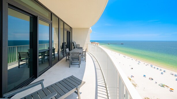 A balcony with a view of the beach, outdoor seating, and a clear sky. - Phoenix Gulf Shores Ii 1403 3 Bedroom Condo (Gulf Shores)