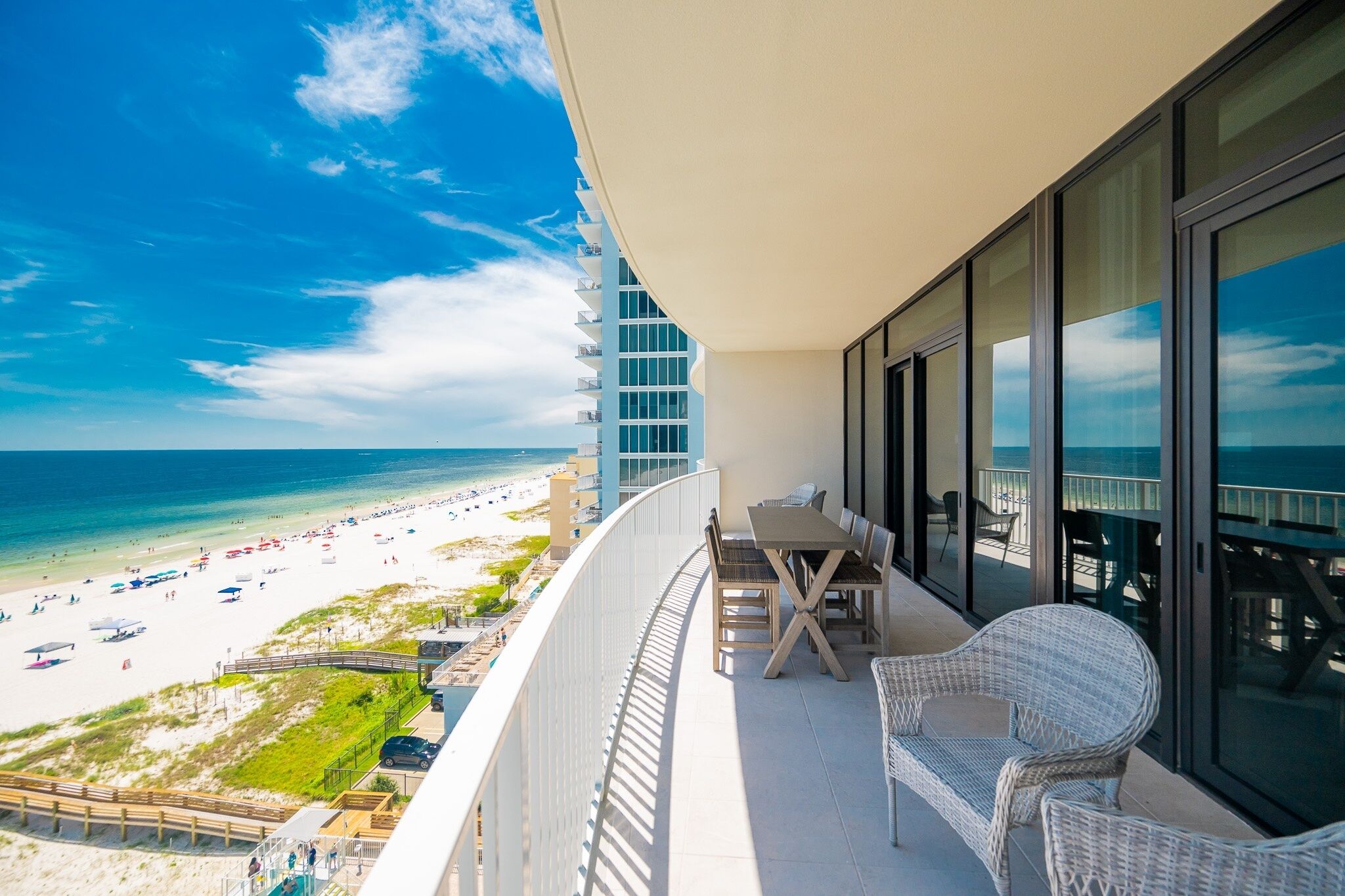 Un balcone con vista sulla spiaggia, un tavolo e sedie in vimini.