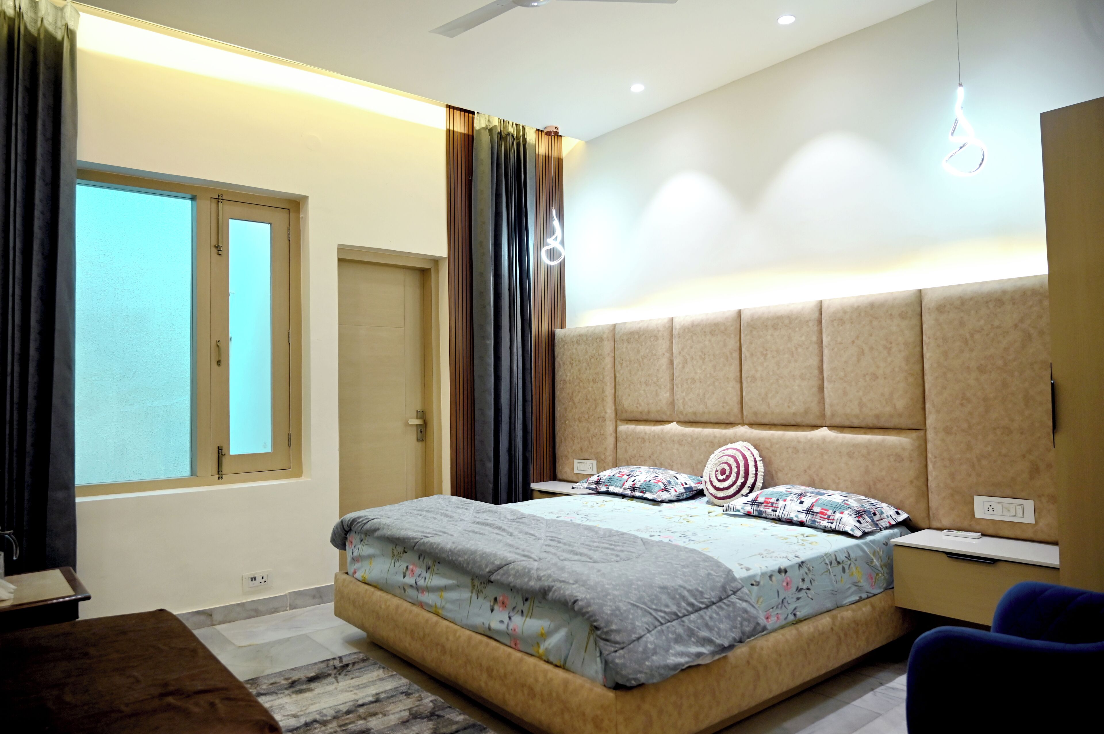 A bedroom with a bed, bedside table, lamp, and curtains.