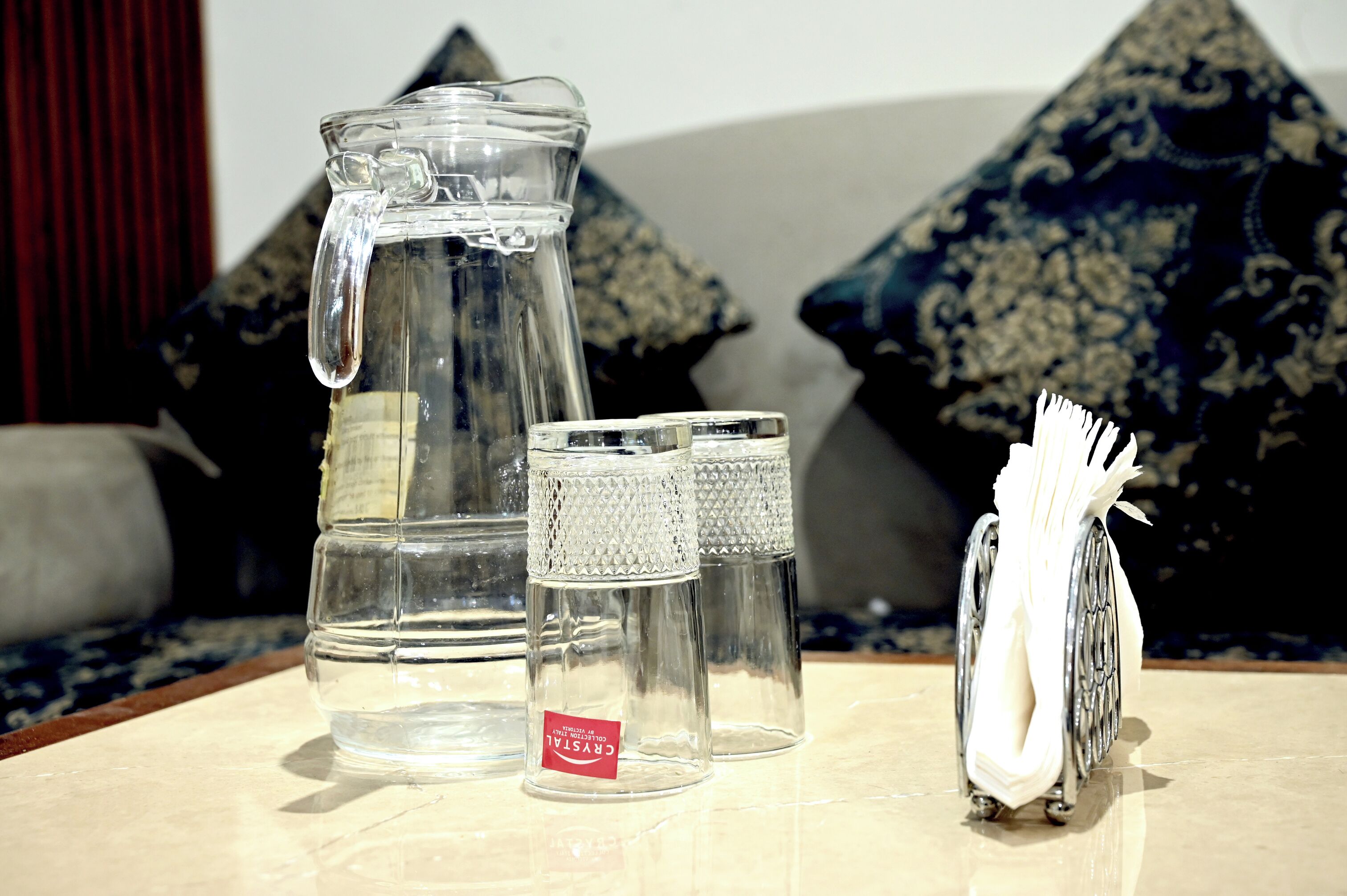 A clear glass pitcher, two small glass containers, and a white object on a table.