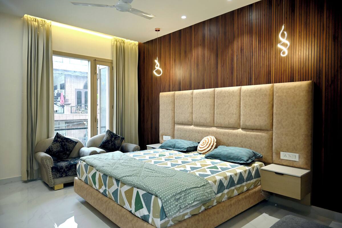 A modern bedroom with a large bed, a chair, a desk, and a view of the outside.