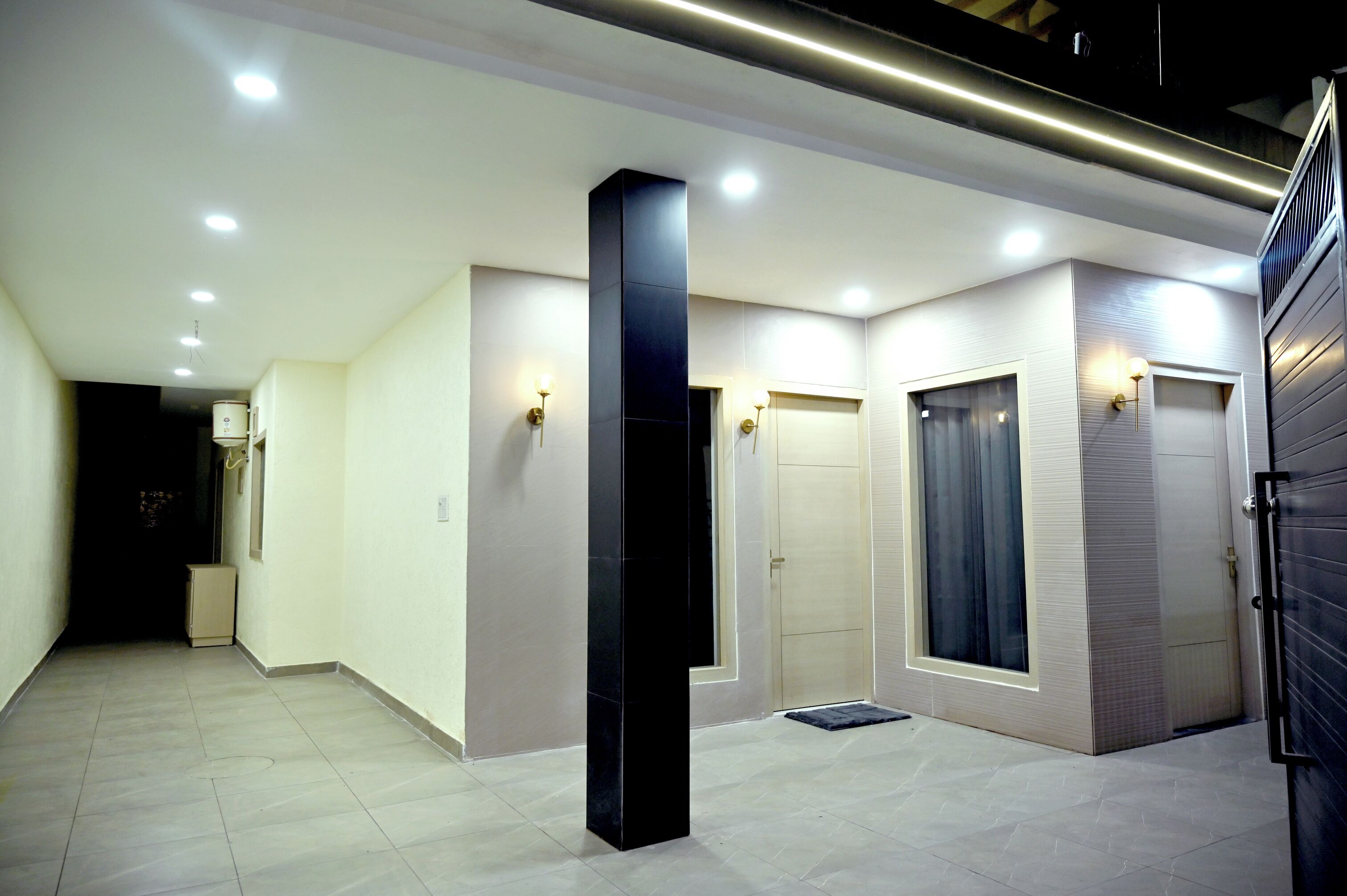 A hallway with recessed lighting, a black pillar, and a door with a window.