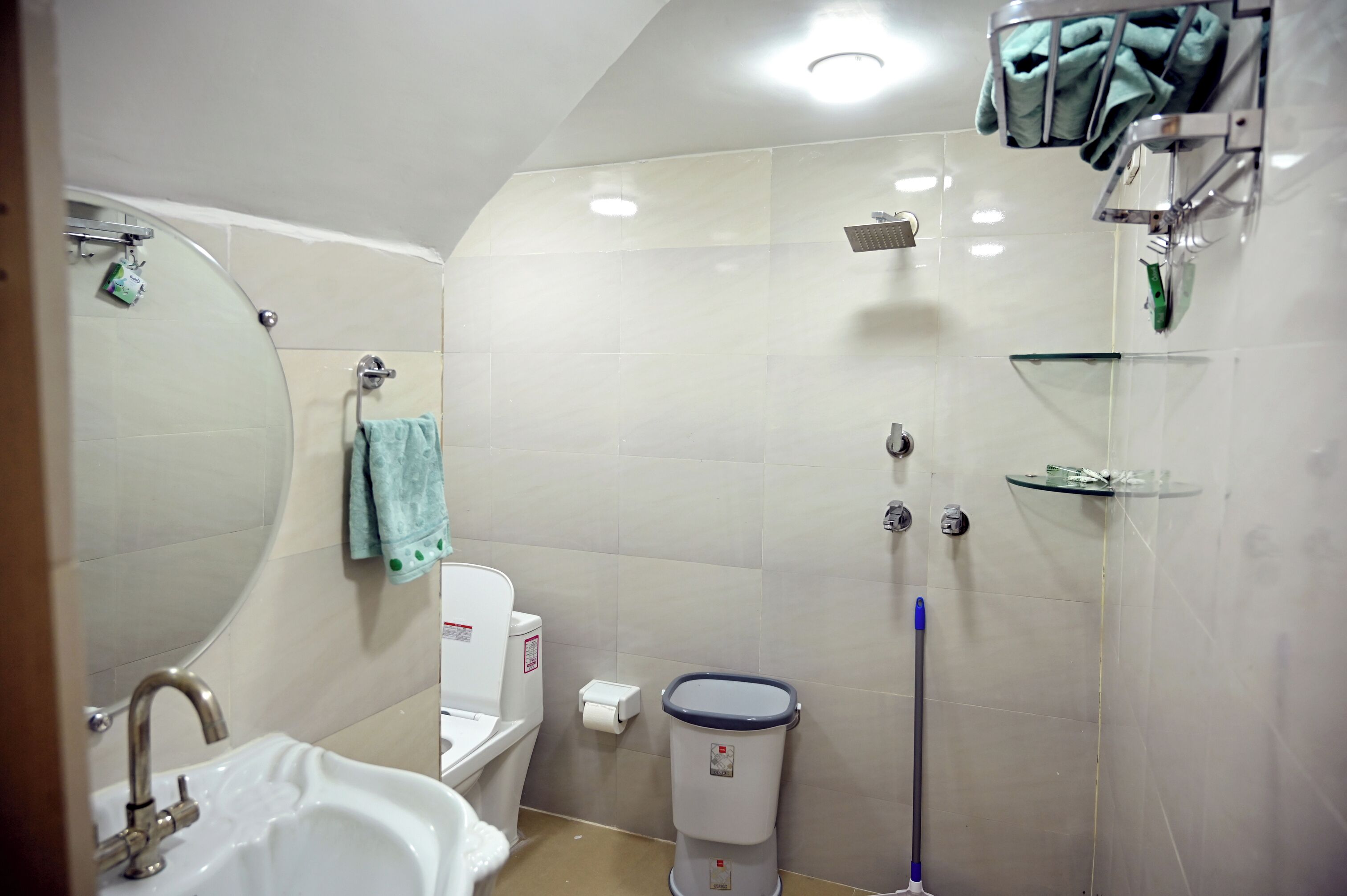 A bathroom with a sink, toilet, mirror, shower, and a towel rack.