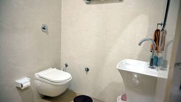 A compact bathroom with a toilet, sink, and shower.