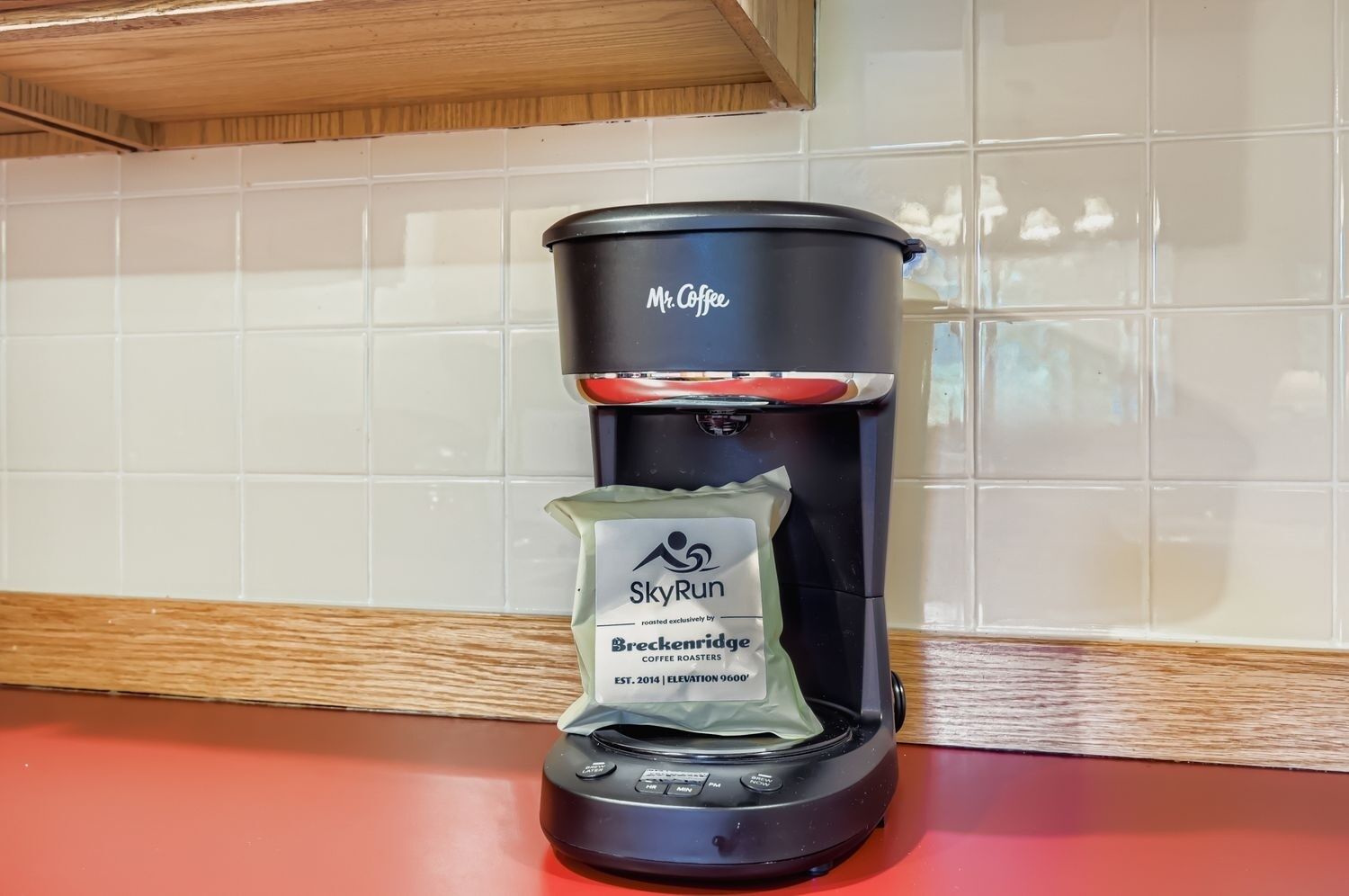 Uma cafeteira com um cápsula de café marcada com 'SkyRun' em uma bancada de cozinha.