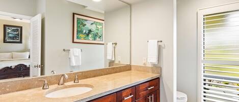 A bathroom with a large mirror, two sinks, a wooden vanity, and a toilet.