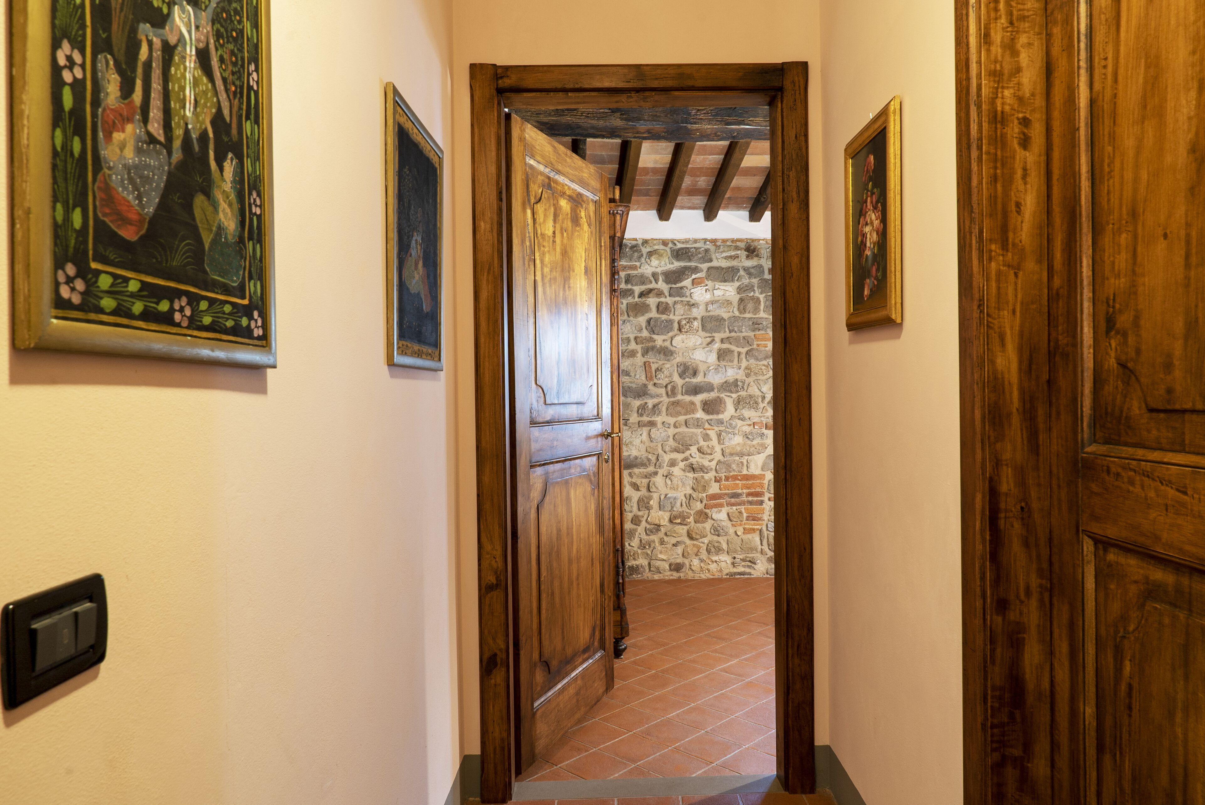 A hallway with wooden doors, stone walls, and tiled flooring.