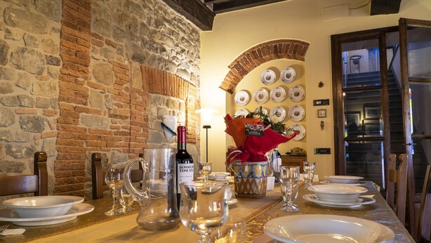 A dining table set for a meal with plates, glasses, and a bottle of wine.