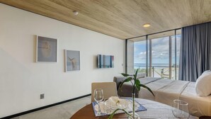 A modern hotel room with a large window, a bed, a seating area, and artwork on the walls. - Nwts - Studios With Side sea View in Maceio III (Maceió)