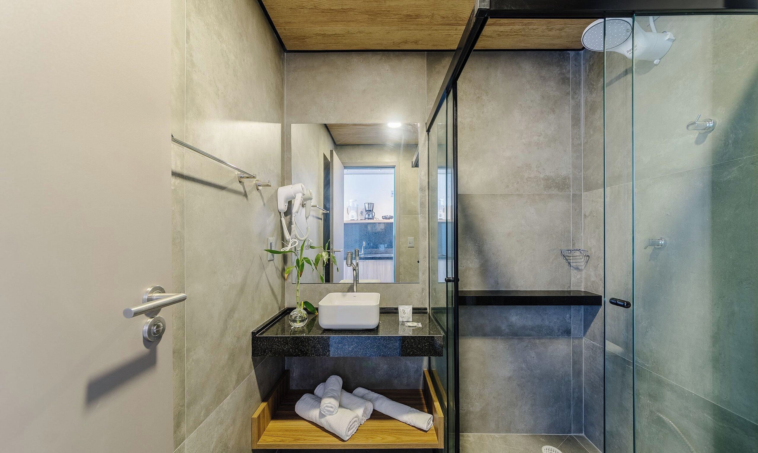 Un baño moderno con cabina de ducha de vidrio, un lavamanos blanco y una encimera de vidrio.