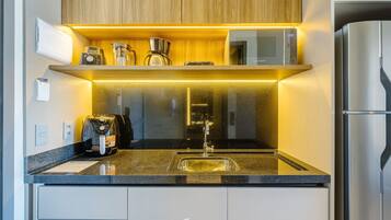 Una cocina moderna con un refrigerador de acero inoxidable, un microondas y una cafetera sobre la encimera.