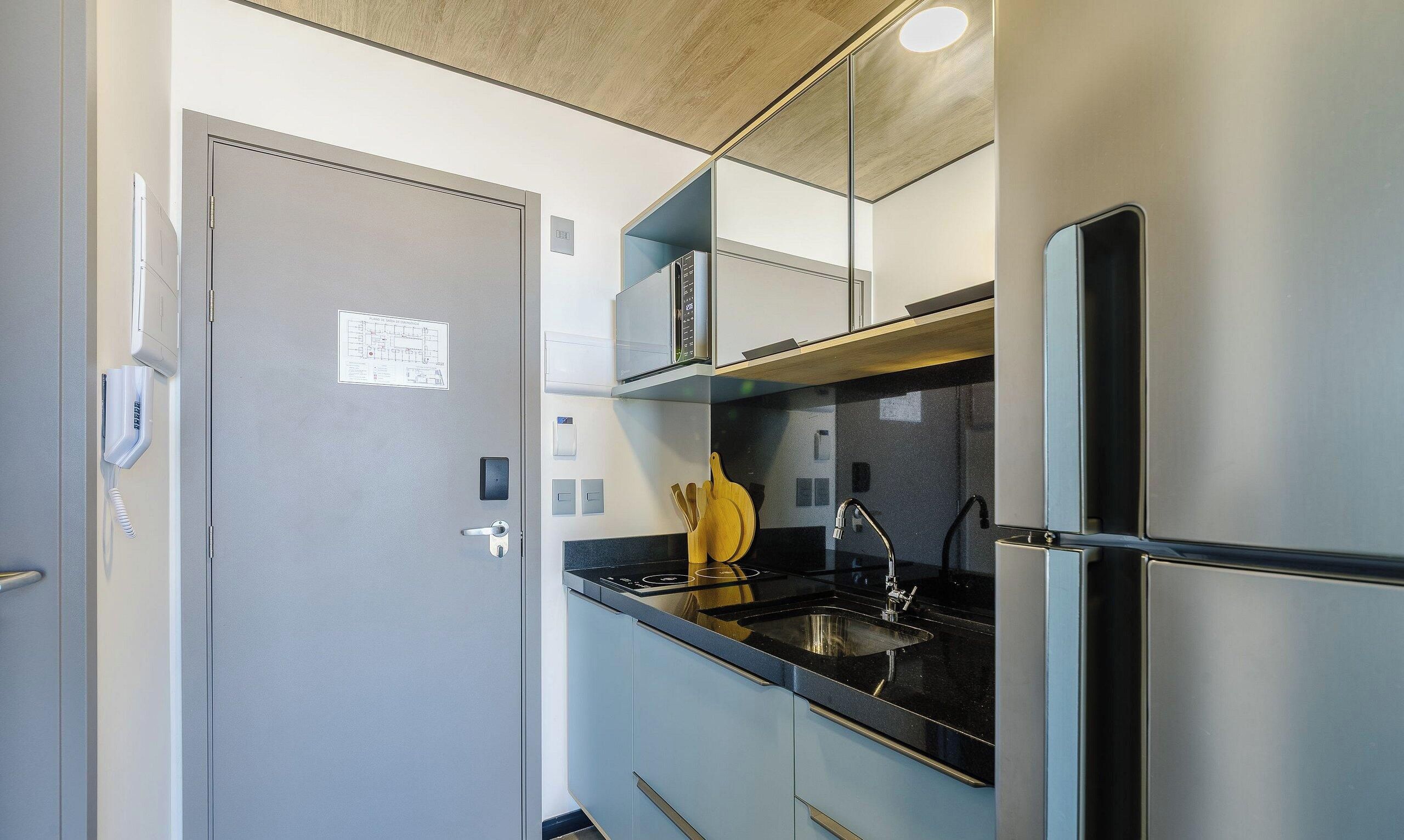Cocina compacta con refrigerador, estufa y lavamanos.