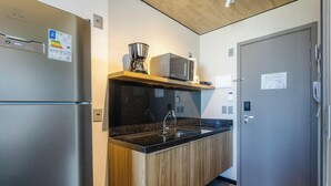 A compact kitchen with a stainless steel refrigerator, a microwave, and a coffee maker on a wooden shelf. - Nwts - Studios With Side sea View in Maceio III (Maceió)