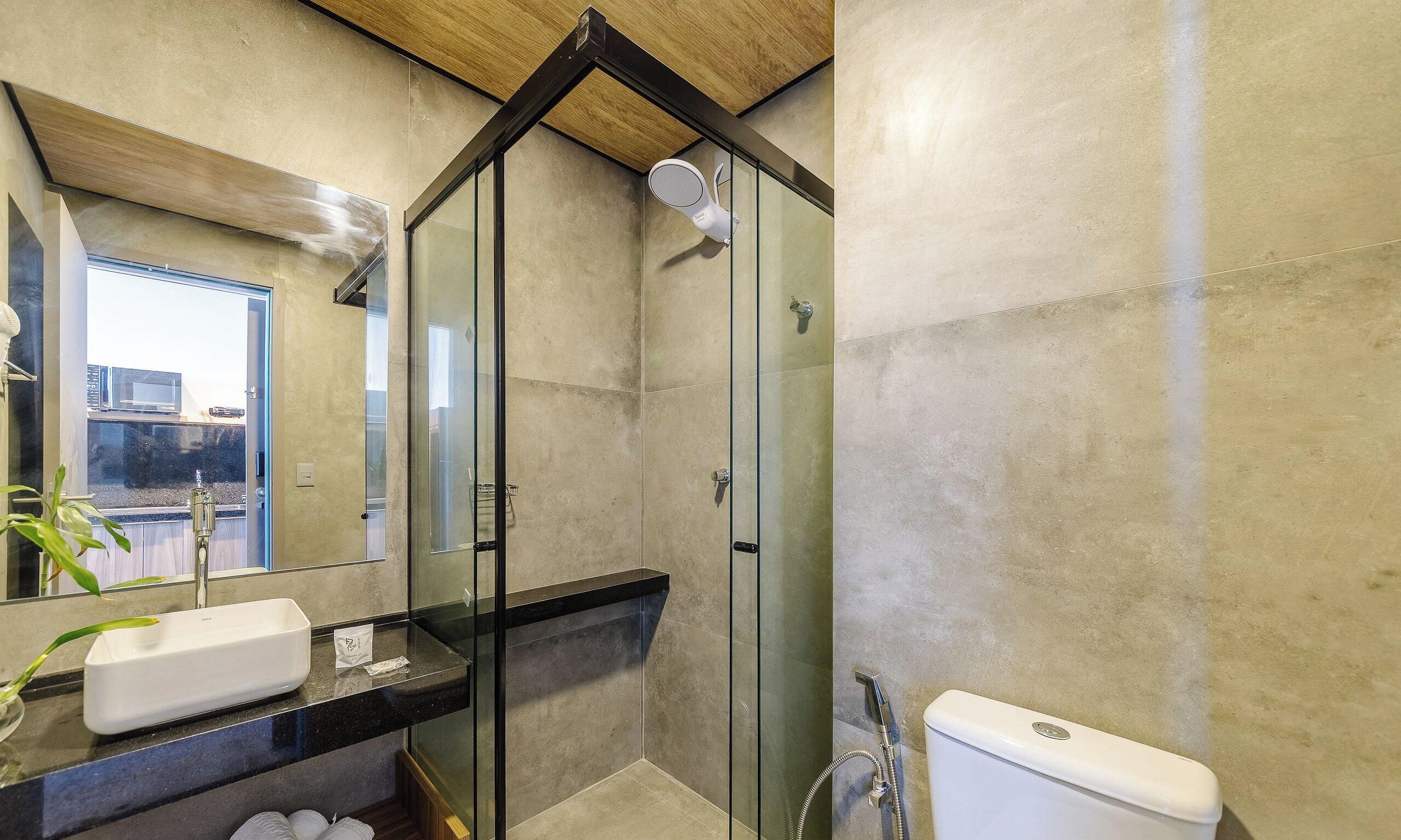 Une salle de bain moderne avec une douche à parois de verre, un lavabo avec un miroir et des toilettes.