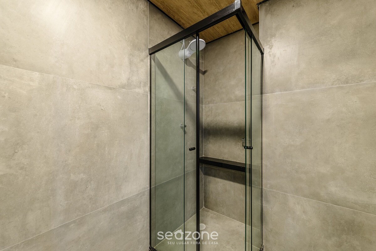 Un espace douche entièrement vitré, doté d’un plafond en bois et de murs carrelés.