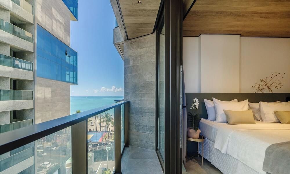 Ein modernes Hotelzimmer mit einem Balkon mit Blick auf eine Skyline und das Meer.