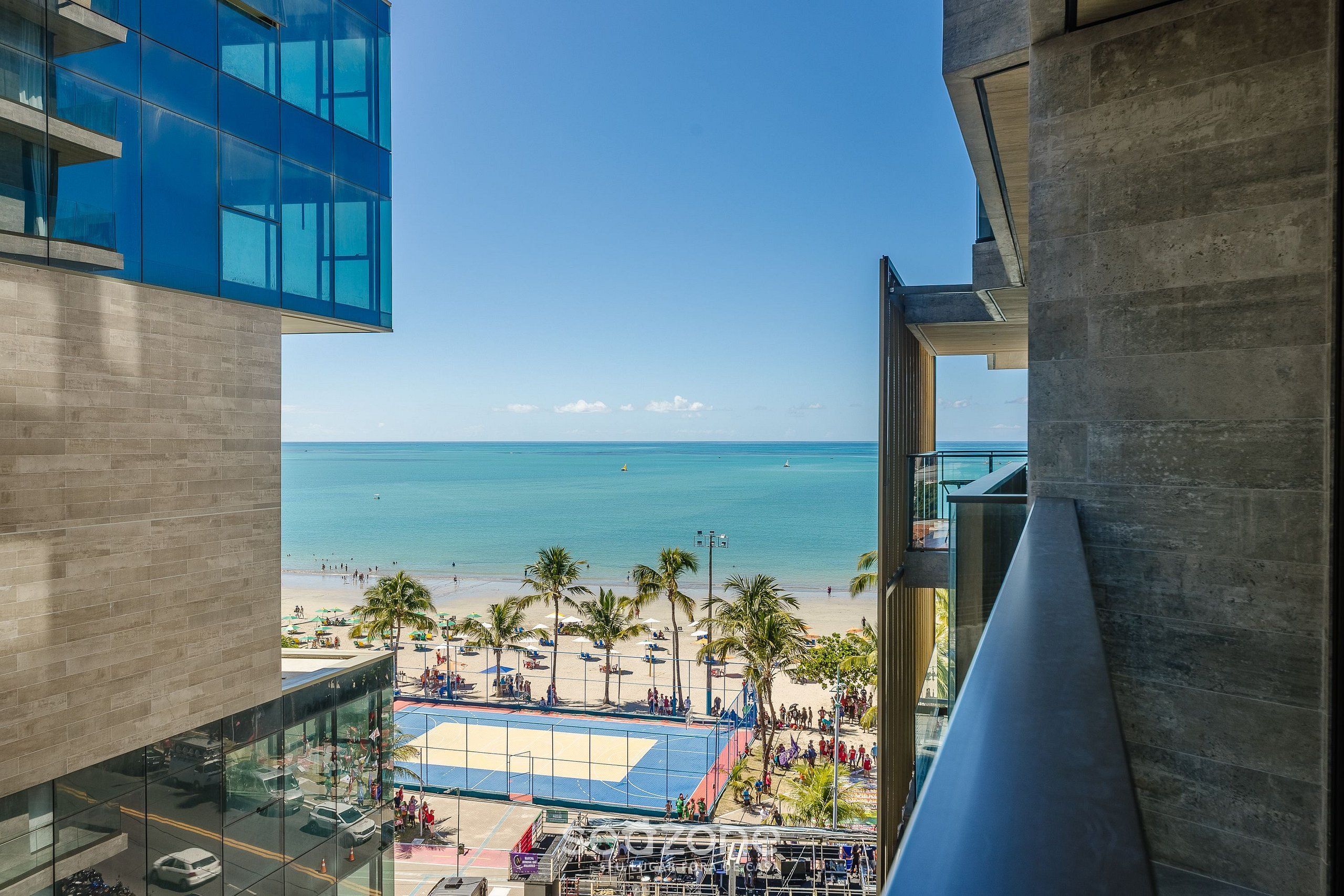 Un edificio alto con vista a una playa y una cancha de voleibol.