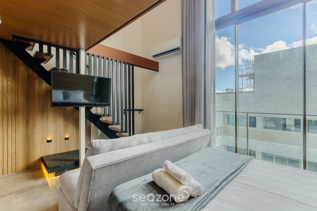 Una habitación de hotel moderna con una cama, un televisor, una pared de madera y un ventanal grande.