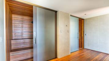 Um corredor com porta deslizante, piso de madeira e parede em tom claro.