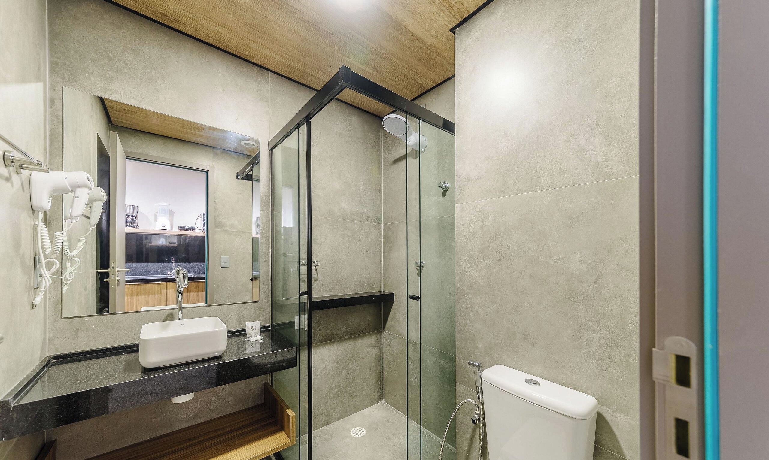 Un baño moderno con cabina de ducha de vidrio, un lavamanos con espejo y un inodoro.