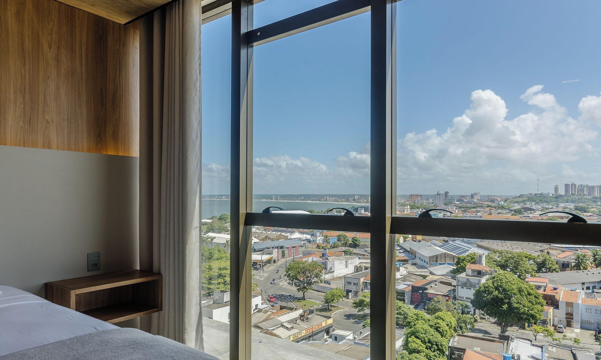 Une chambre d’hôtel dotée d’une grande fenêtre donnant sur la ville.