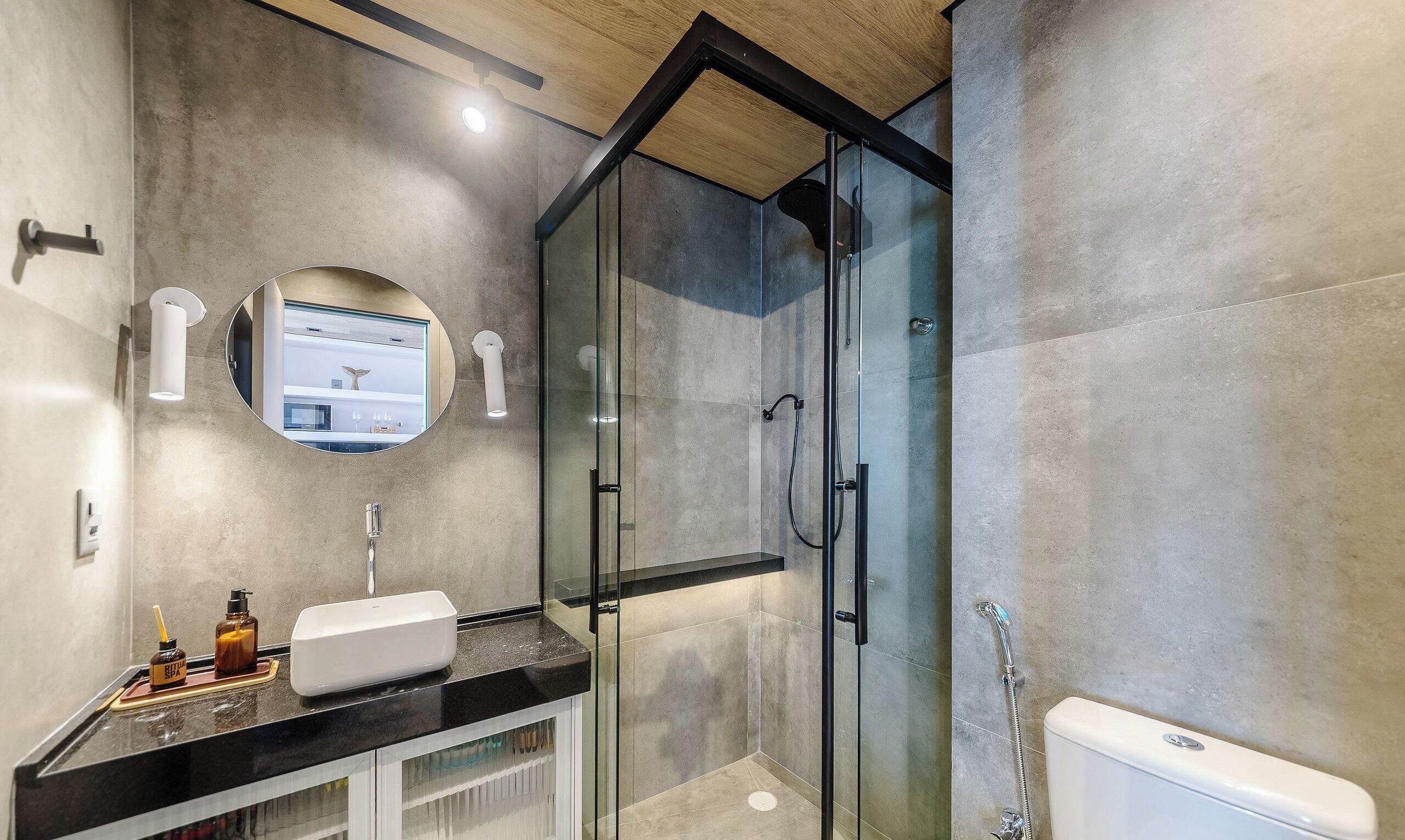A modern bathroom with a glass shower enclosure, a white sink, and a mirror with a built-in light.