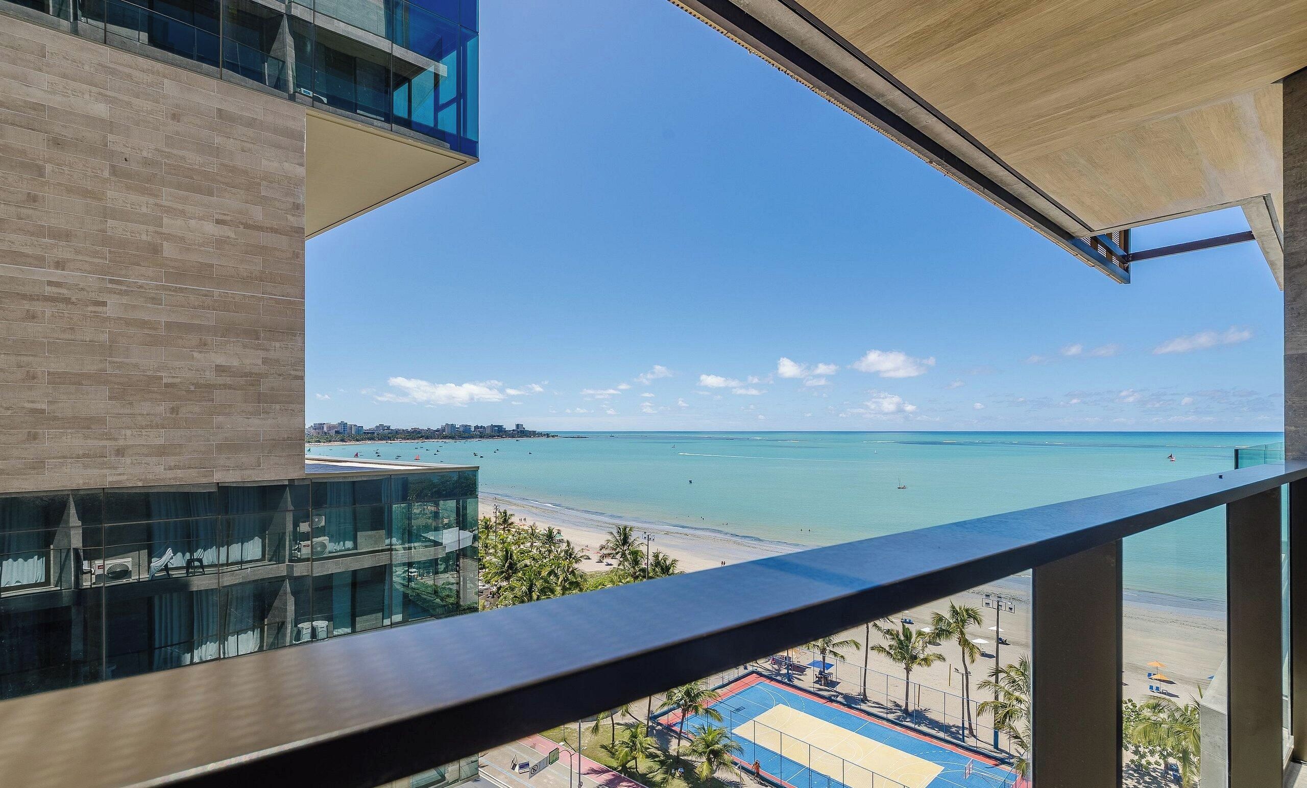 A balcony with a view of a beach and a clear sky.