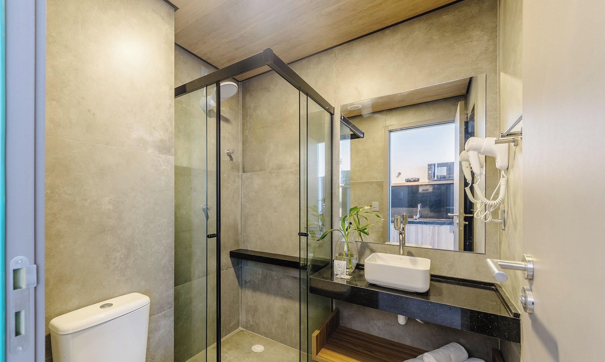 Un baño moderno con cabina de ducha de vidrio, un lavabo blanco y un espejo grande.