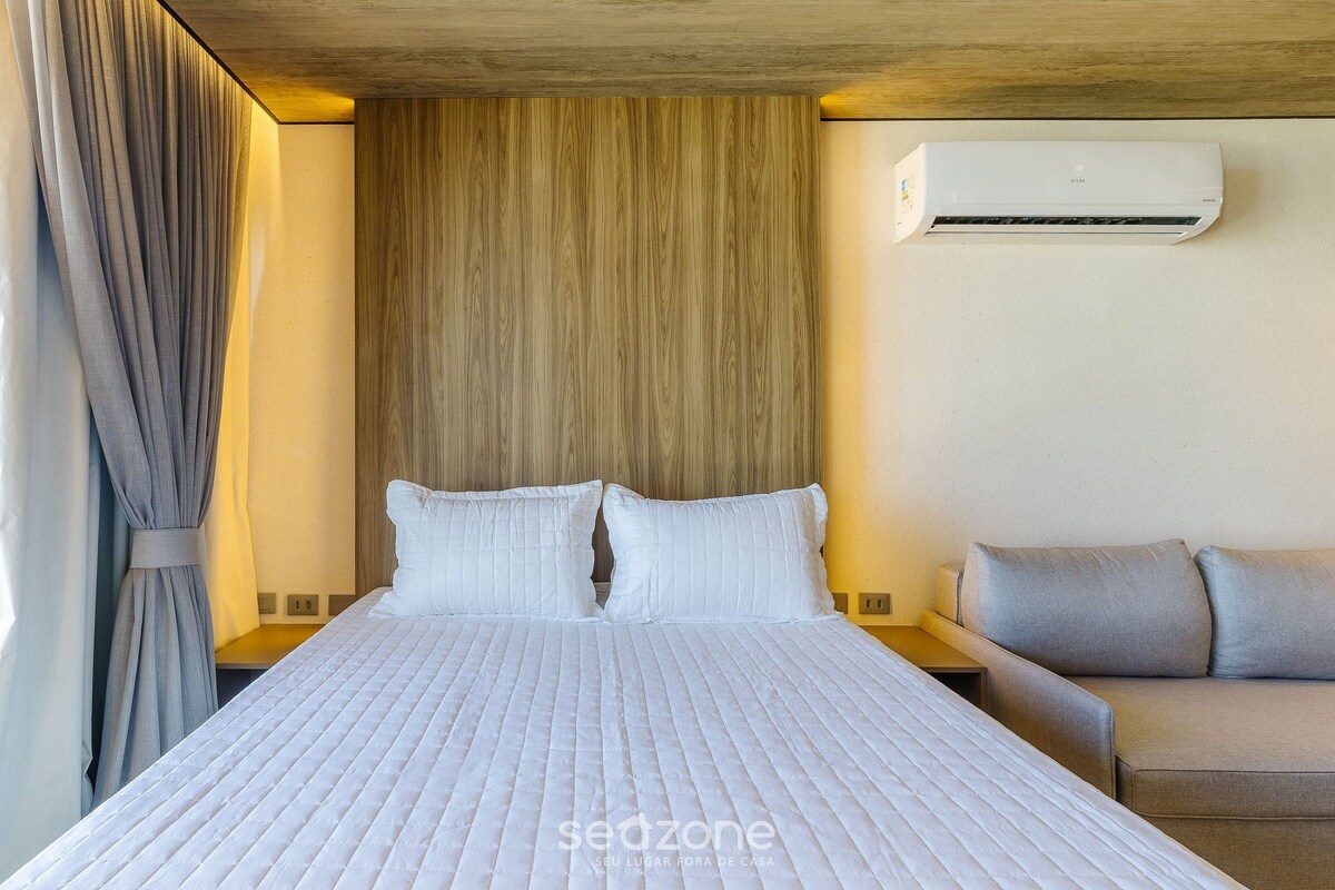 Una habitación de hotel con cama, sofá, aire acondicionado de pared y cortina.