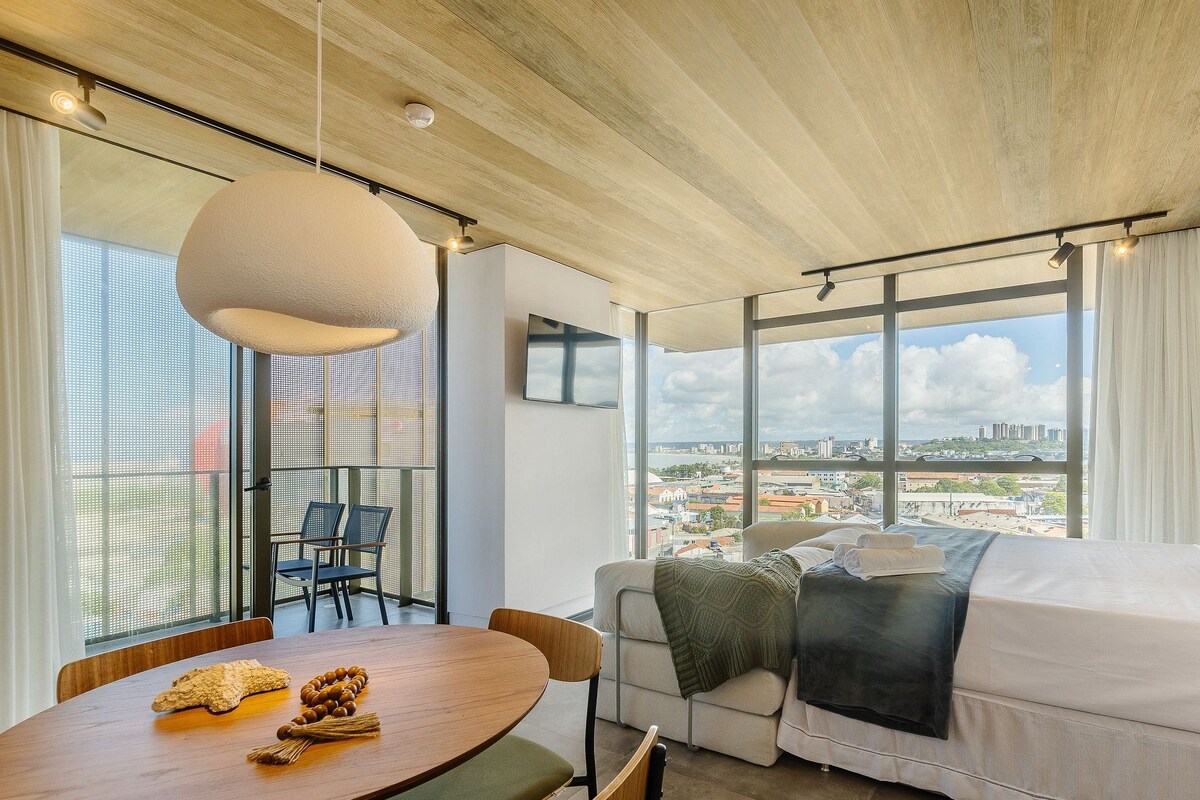 Une pièce moderne dotée d’une grande fenêtre, d’un canapé, d’une table à manger et d’un plafond avec des poutres apparentes.