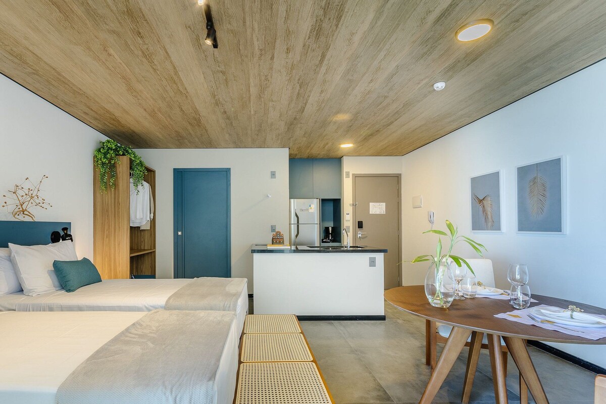 Une chambre d’hôtel moderne dotée d’un grand lit, d’une petite kitchenette et d’un coin repas.