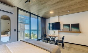 A modern hotel room with a large bed, a balcony with a view of the sea, a small dining area, and a TV on the wall. - Nwts - Studios With Side sea View in Maceio III (Maceió)