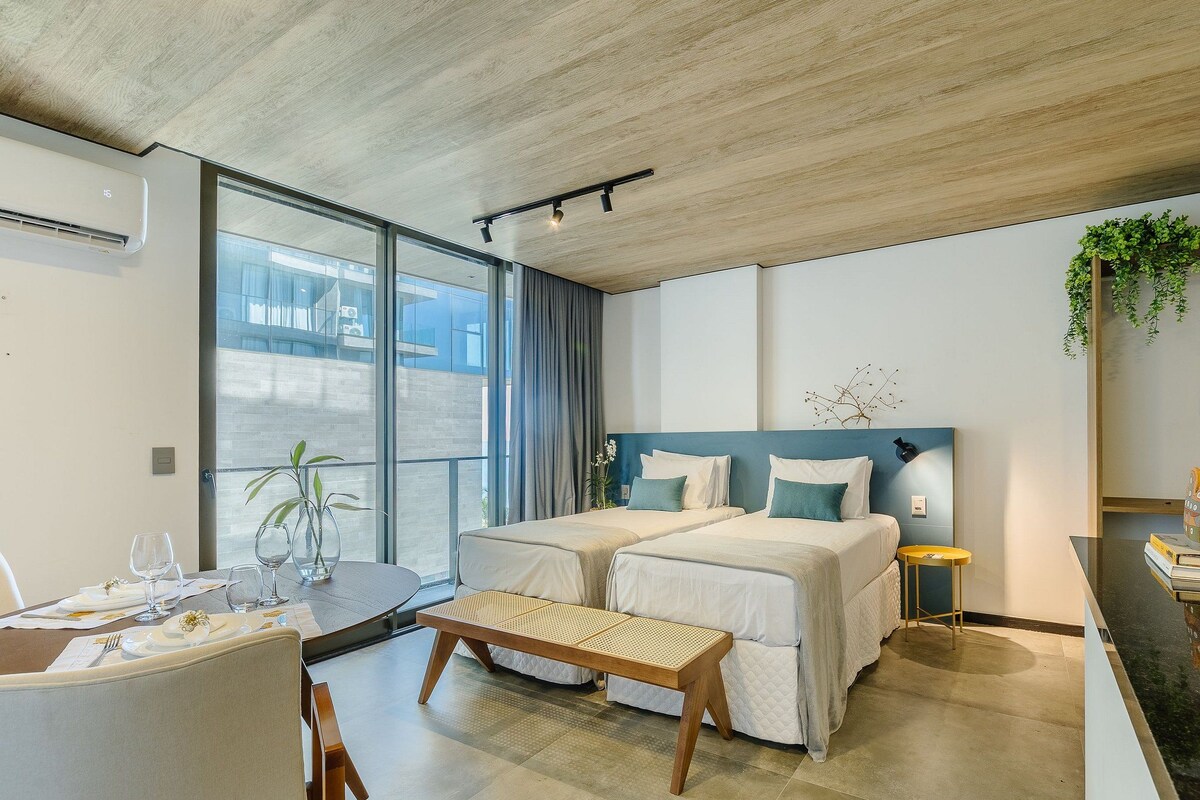 Una habitación de hotel moderna con una cama grande, un escritorio pequeño, una mesa de comedor y un balcón con vistas.