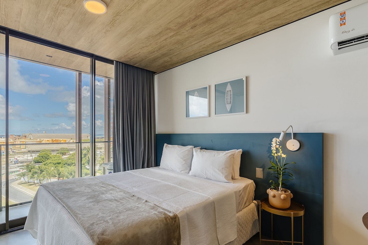 Una habitación de hotel moderna con una cama grande, vistas de la ciudad y un ventilador de techo.