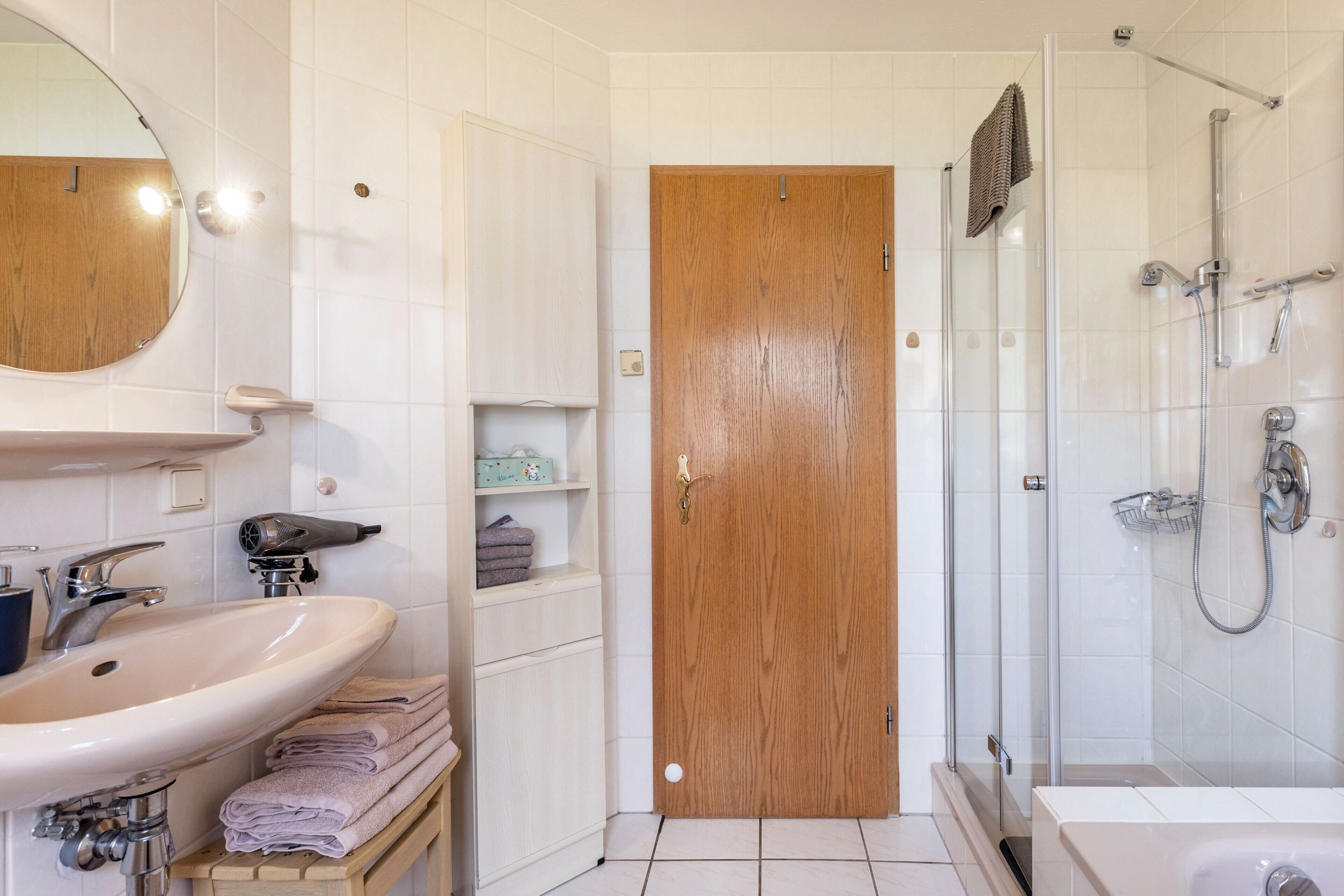 Une salle de bain équipée d’un lavabo, d’un miroir, d’un porte-serviettes et d’une zone douche.