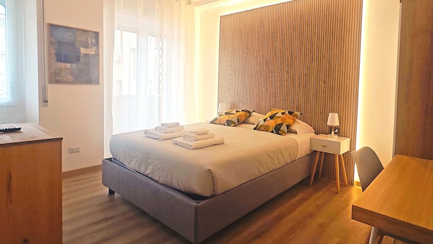 A modern hotel room with a large bed, bedside tables, a desk, and a dining area. - Apartment near Piazza del Popolo (Roma)
