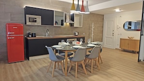 A modern kitchen with a red refrigerator, a microwave, and a sink. There is a dining table with chairs and a small cabinet with a mirror. - Apartment near Piazza del Popolo (Roma)