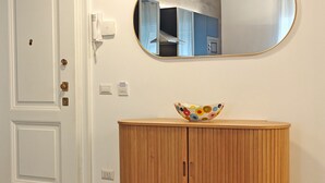 A room with a wooden cabinet, a white door, and a round mirror on the wall. - Apartment near Piazza del Popolo (Roma)
