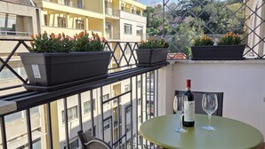 A balcony with potted plants, a table with a bottle and glass, and a chair. - Apartment near Piazza del Popolo (Roma)