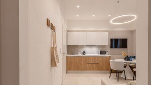 A modern kitchen with wooden cabinets, a microwave, and a dining area with a white table and chairs. - Eternity Apartment – Luxury in the City (Civitanova Marche)